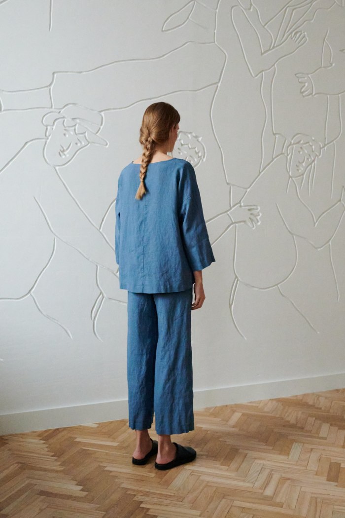 Back of a woman wearing a high-low hem linen top paired with linen trousers