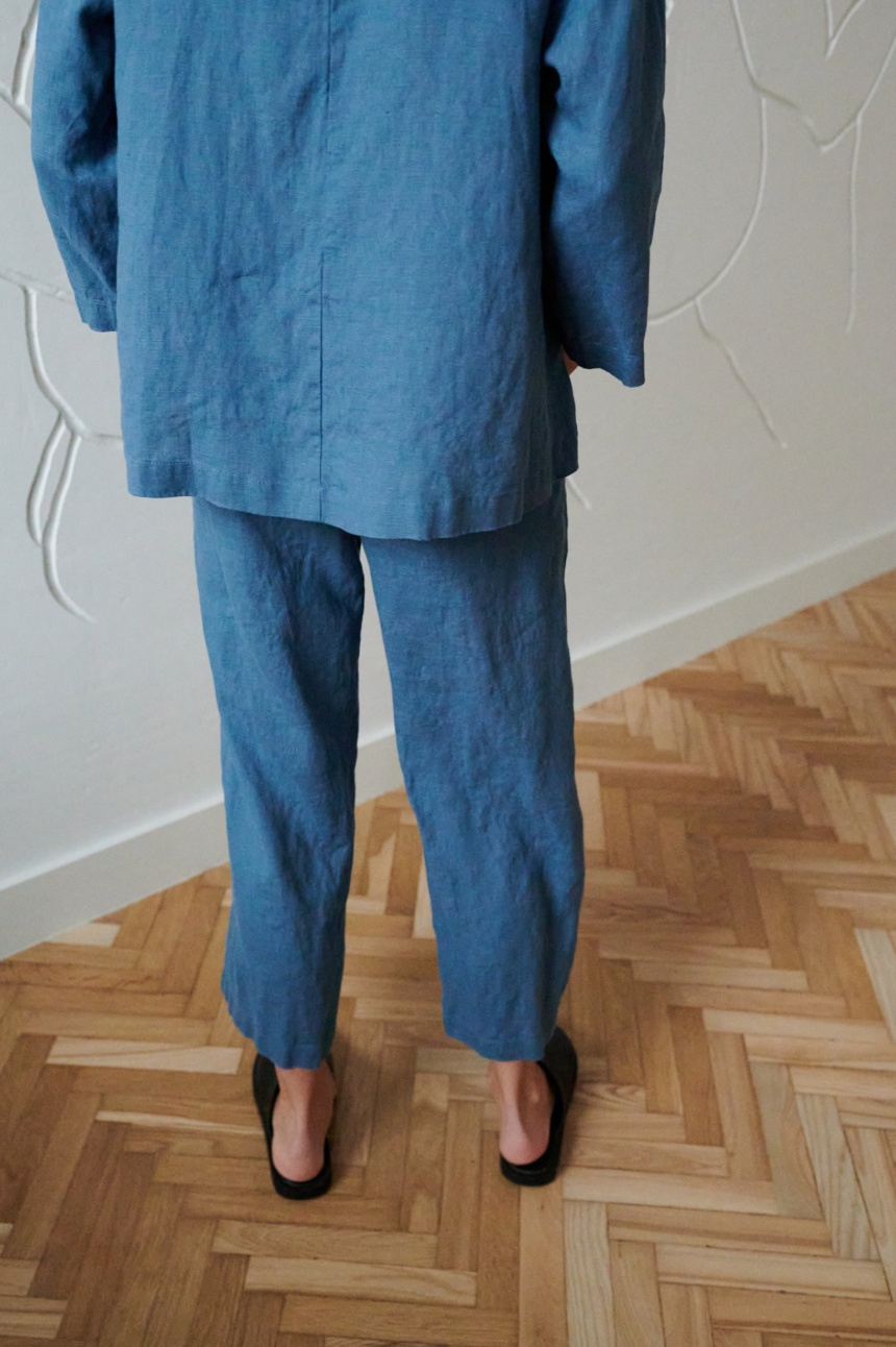 Back of a model in loose-fitting linen trousers and an oversized linen tunic