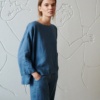 Model wearing a blue loose-fitting linen tunic and matching linen trousers outfit