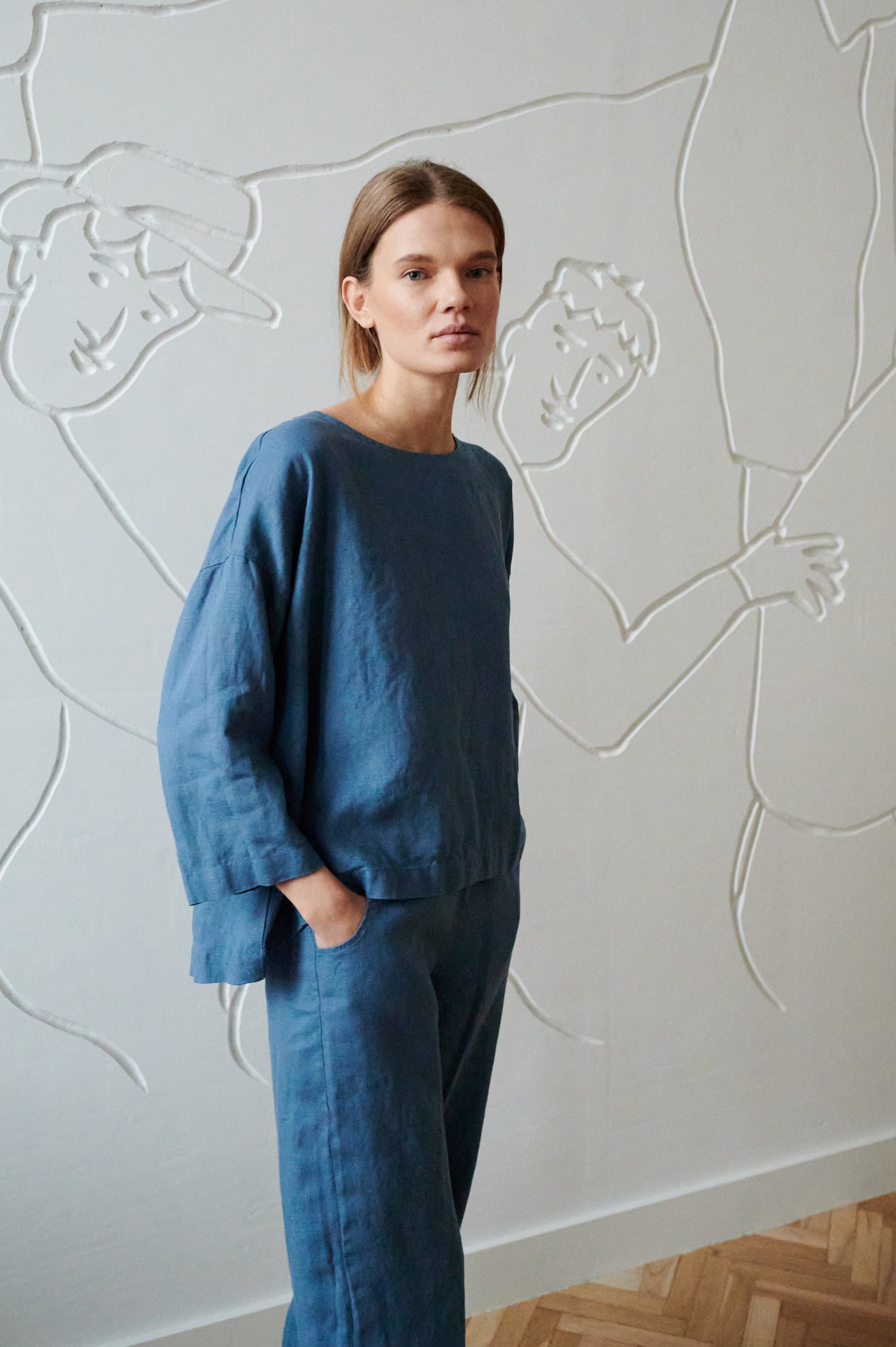 Model wearing a blue loose-fitting linen tunic and matching linen trousers outfit