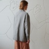 Back of a model in an oversized grey linen jacket with buttoned cuffs