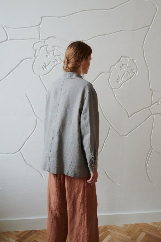 Back of a model in an oversized grey linen jacket with buttoned cuffs