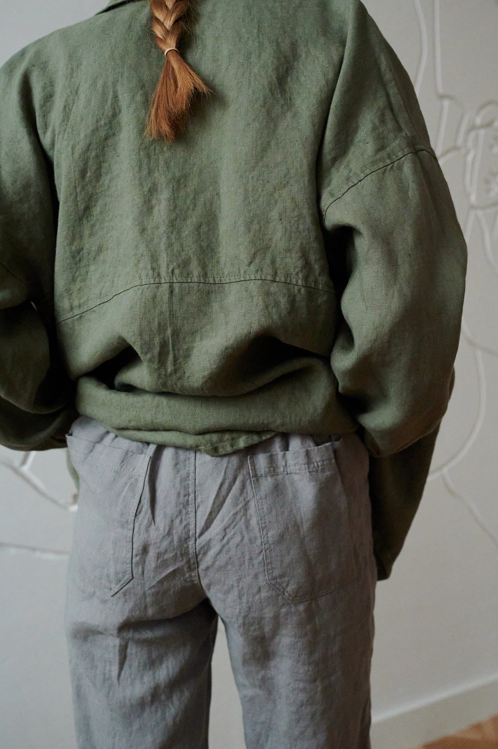 Back of a model wearing high-waisted linen trousers with pockets in the back