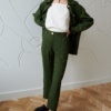 Woman in high-waisted green linen trousers and a matching linen jacket outfit paired with a white linen top