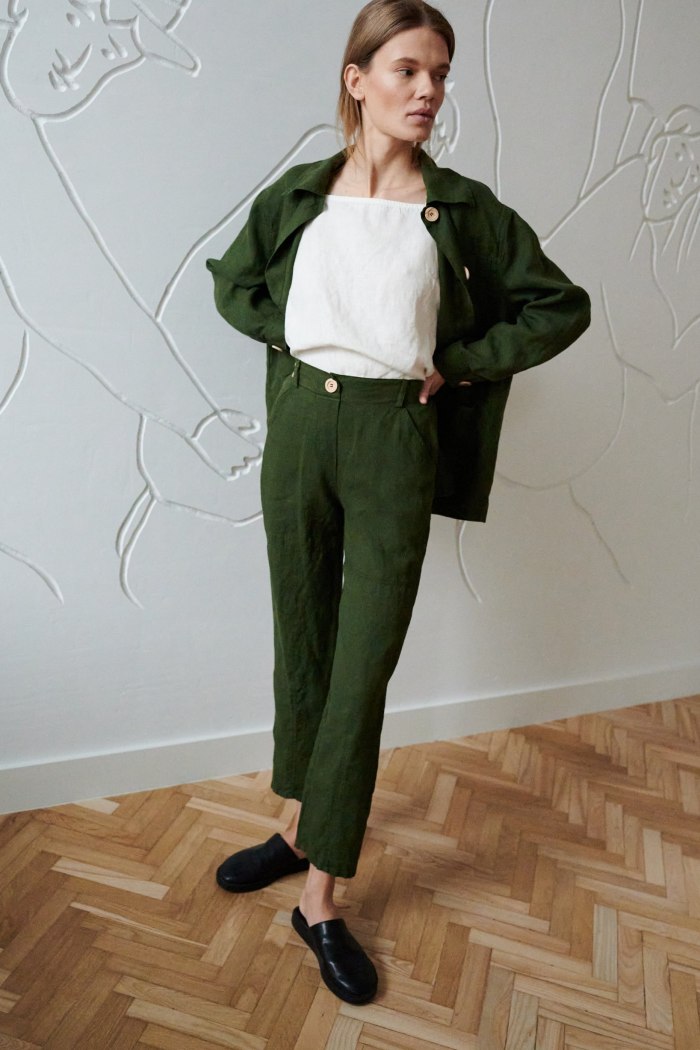 Woman in high-waisted green linen trousers and a matching linen jacket outfit paired with a white linen top