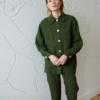 Model in a forest green linen jacket with wooden buttons and loose fitting linen pants