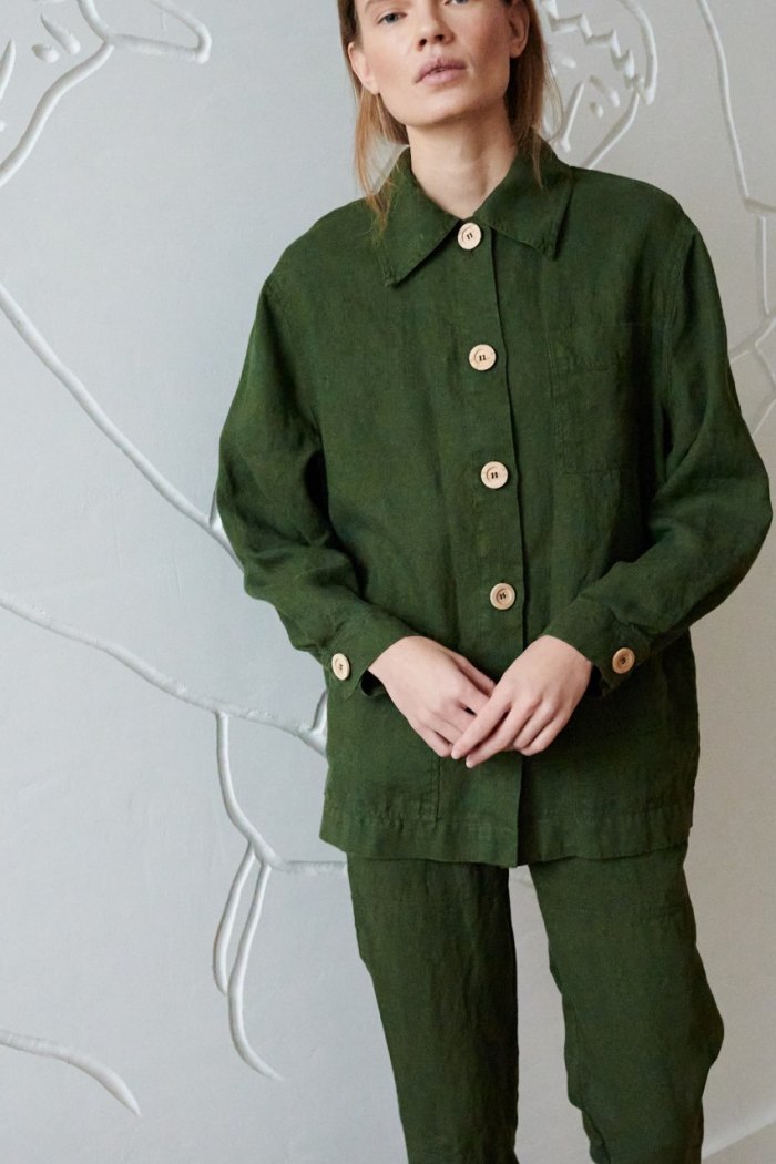 Model in a forest green linen jacket with wooden buttons and loose fitting linen pants