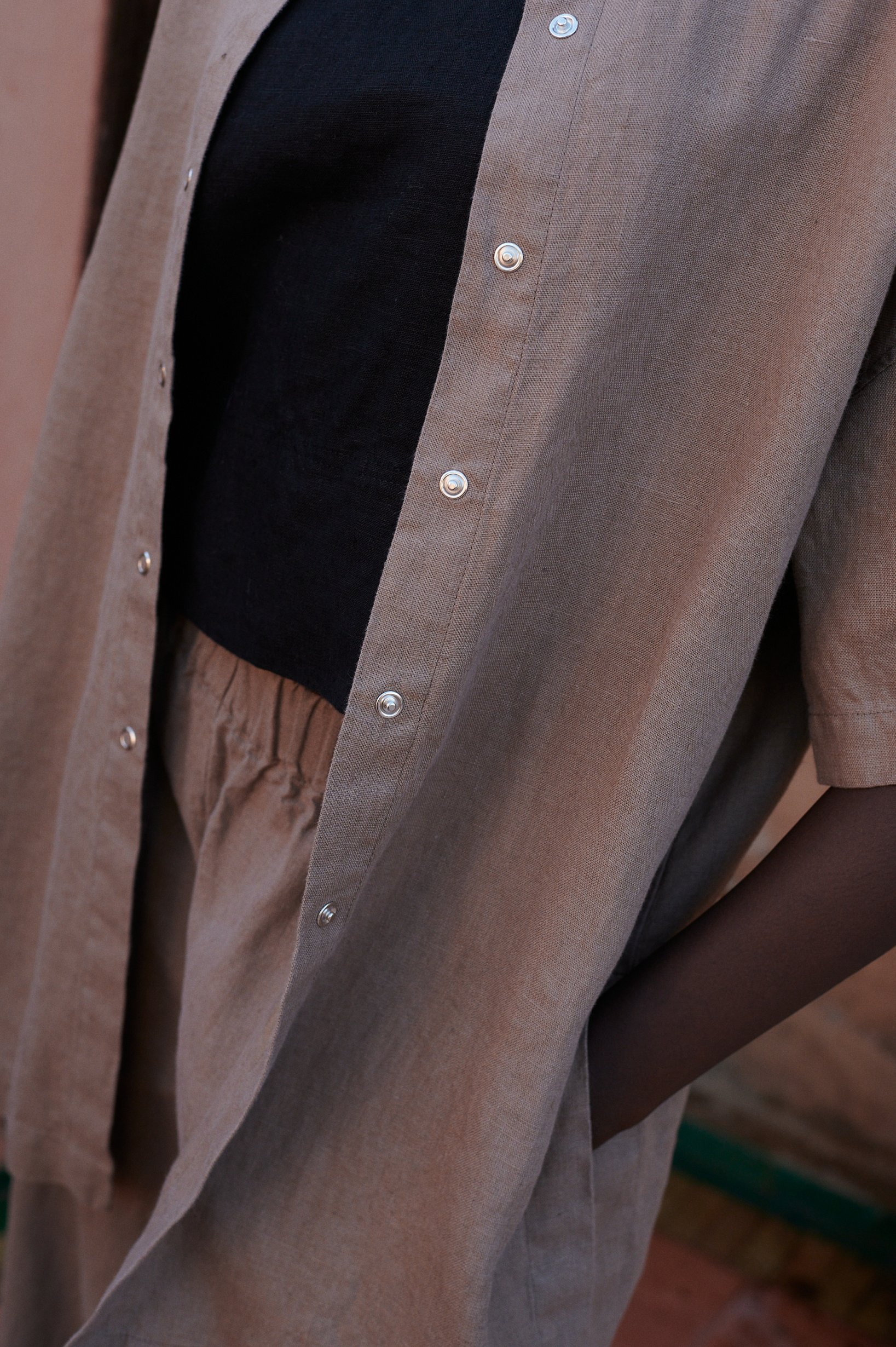 a close up of a linen set of short-sleeved linen shirt with snap closure, and wide leg trousers in mocha mousse
