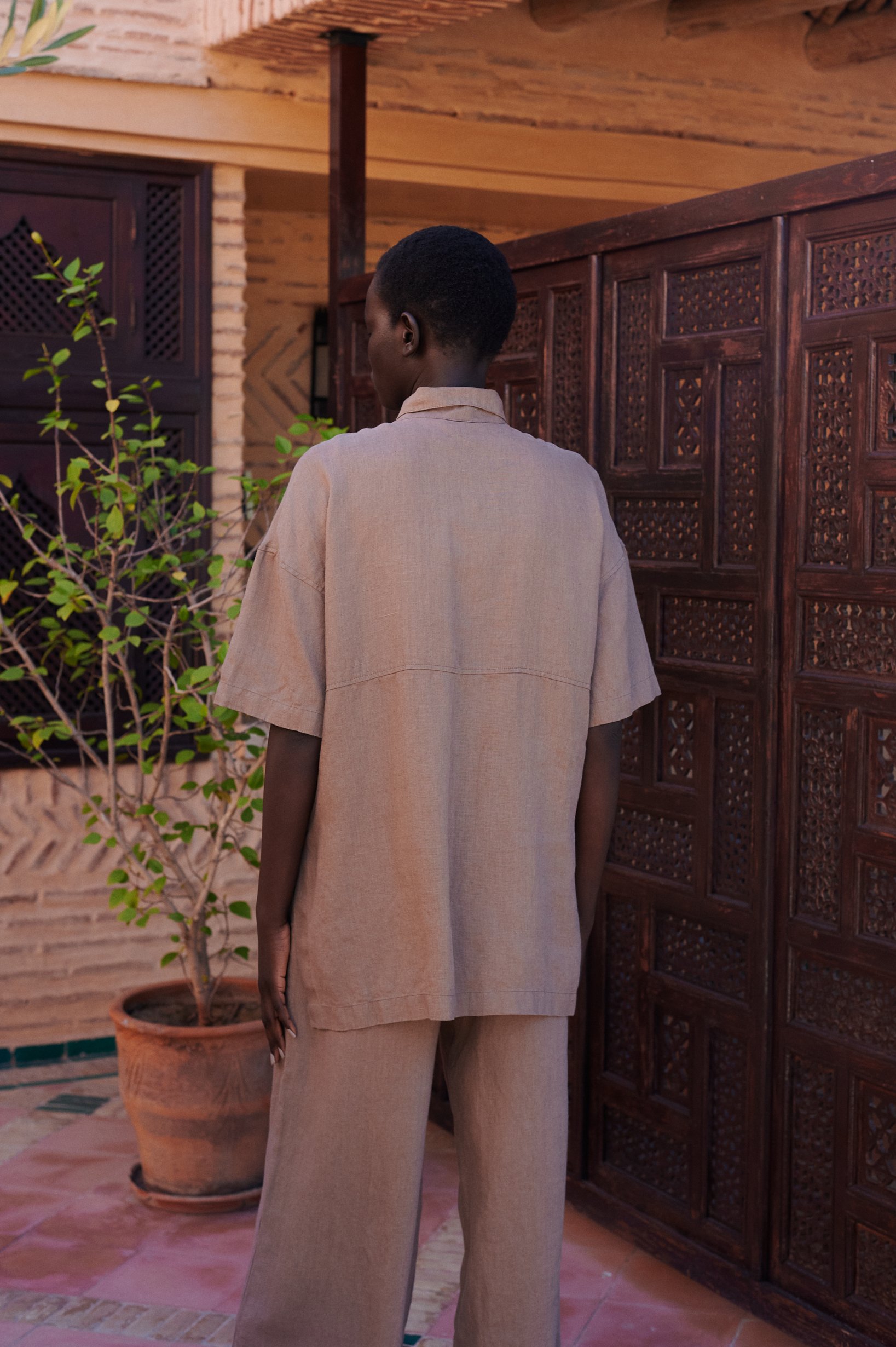 a back view of a linen set of short-sleeved linen shirt, and wide leg trousers in mocha mousse