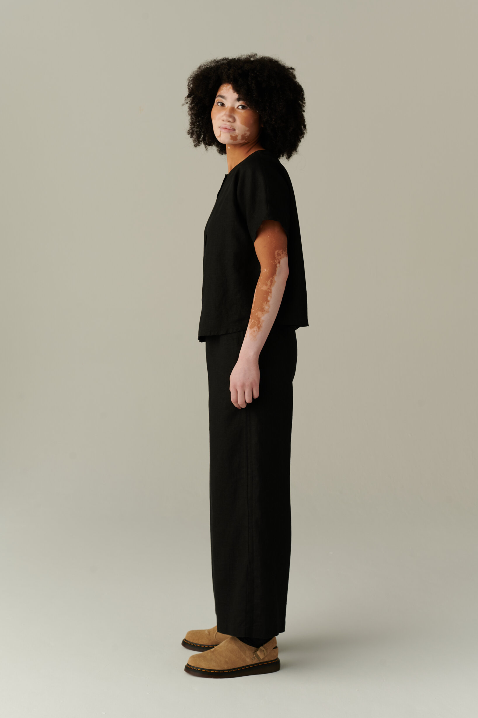Model wearing loose-fitting black linen trousers and a matching linen top