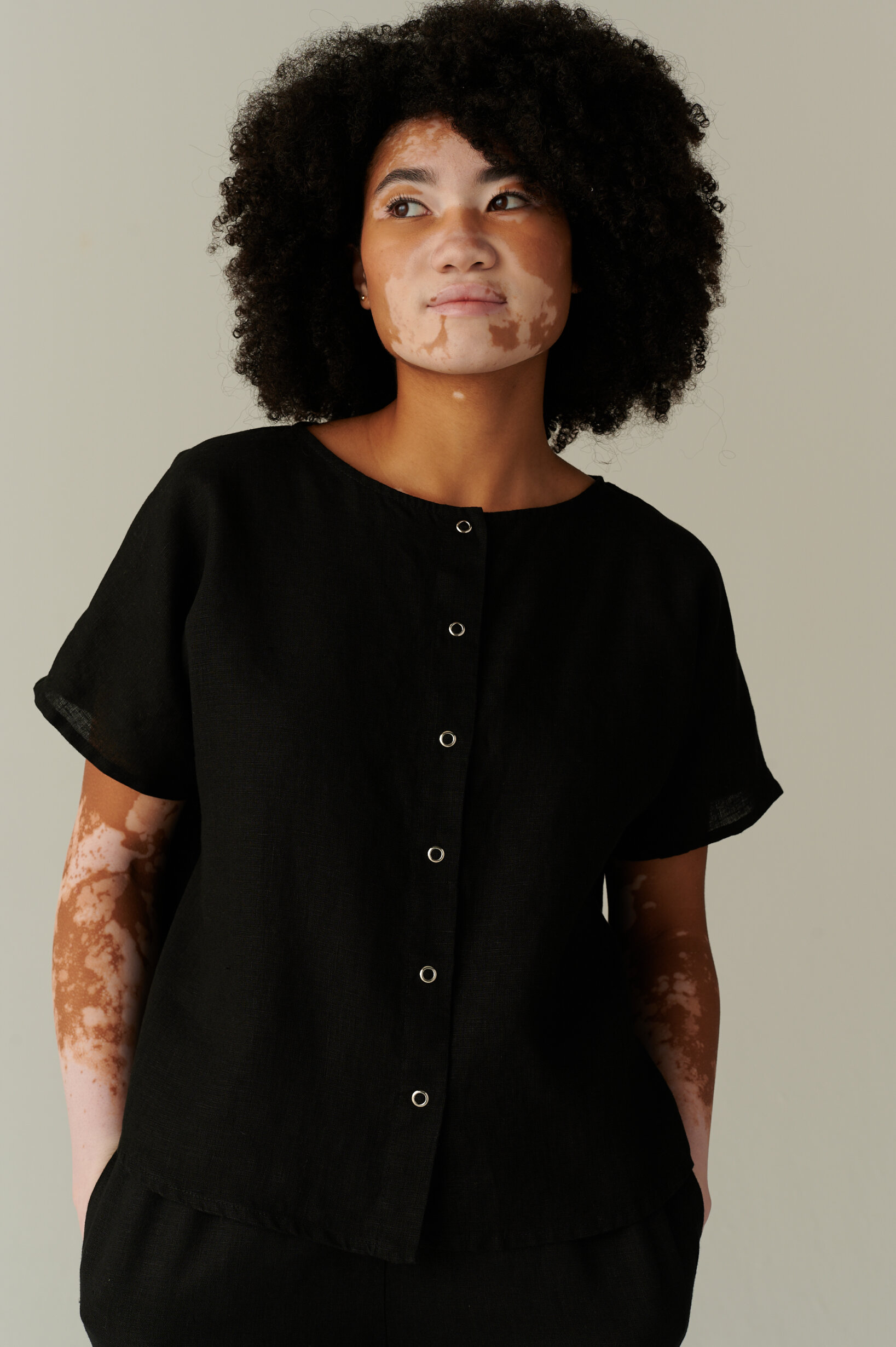 A model wearing a black short sleeve linen shirt with snap buttons