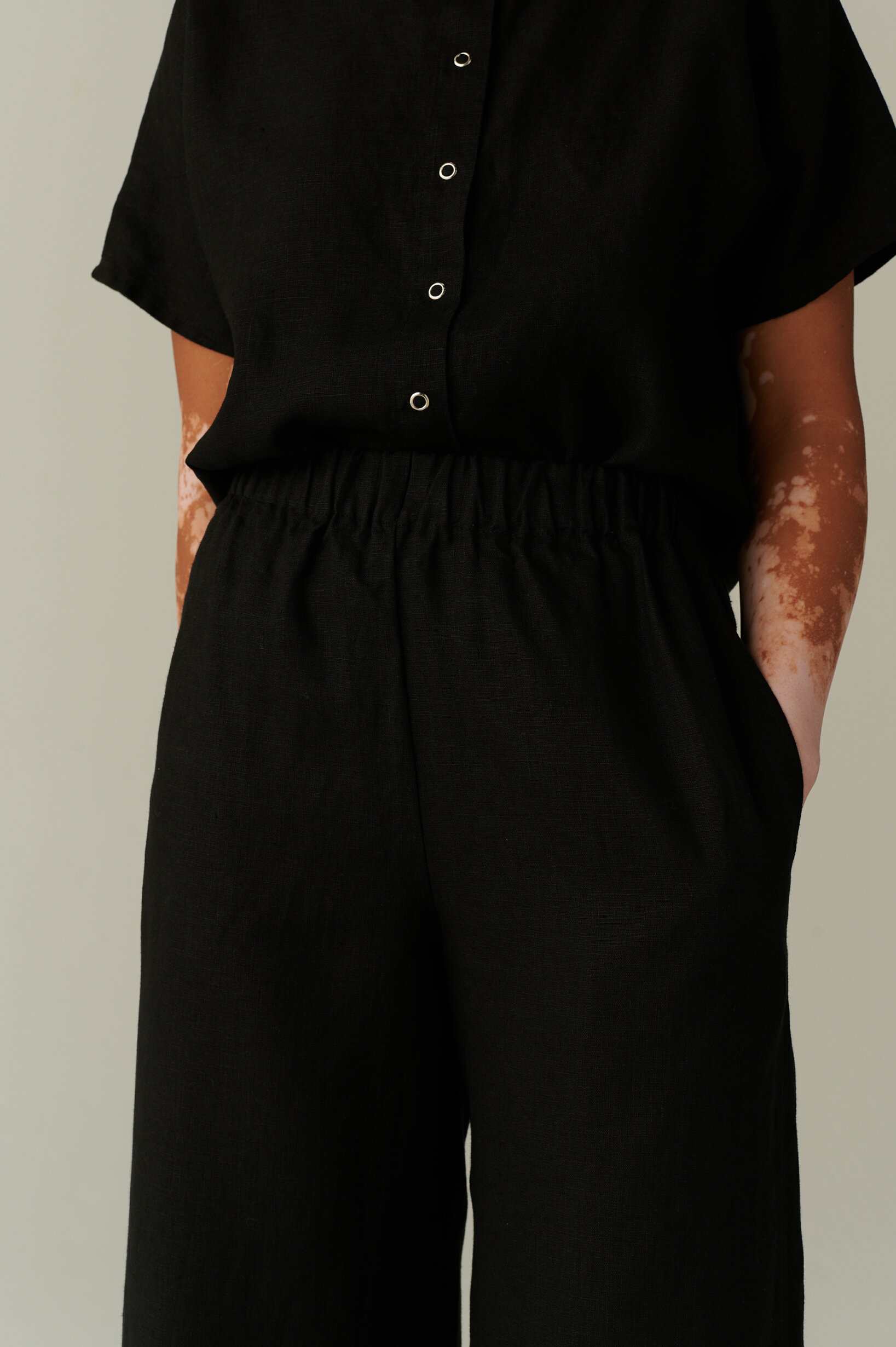 Loose fitting black linen shirt tucked into an elasticated waistband of linen trousers with pockets