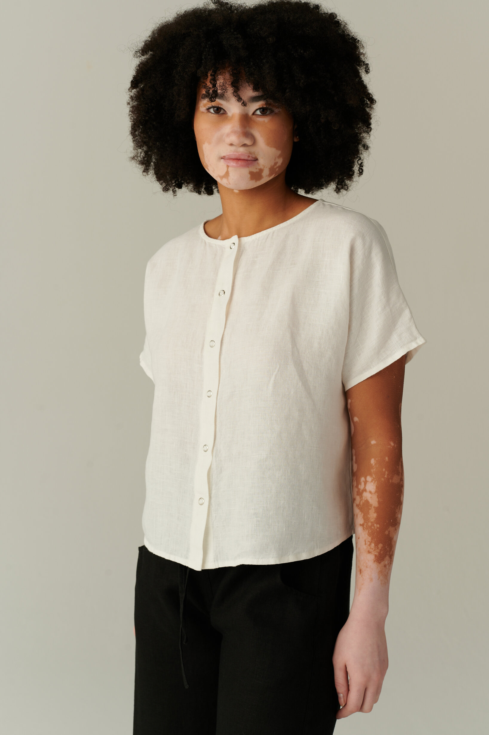 White linen top with short, wide sleeves and dropped shoulders paired with black linen pants