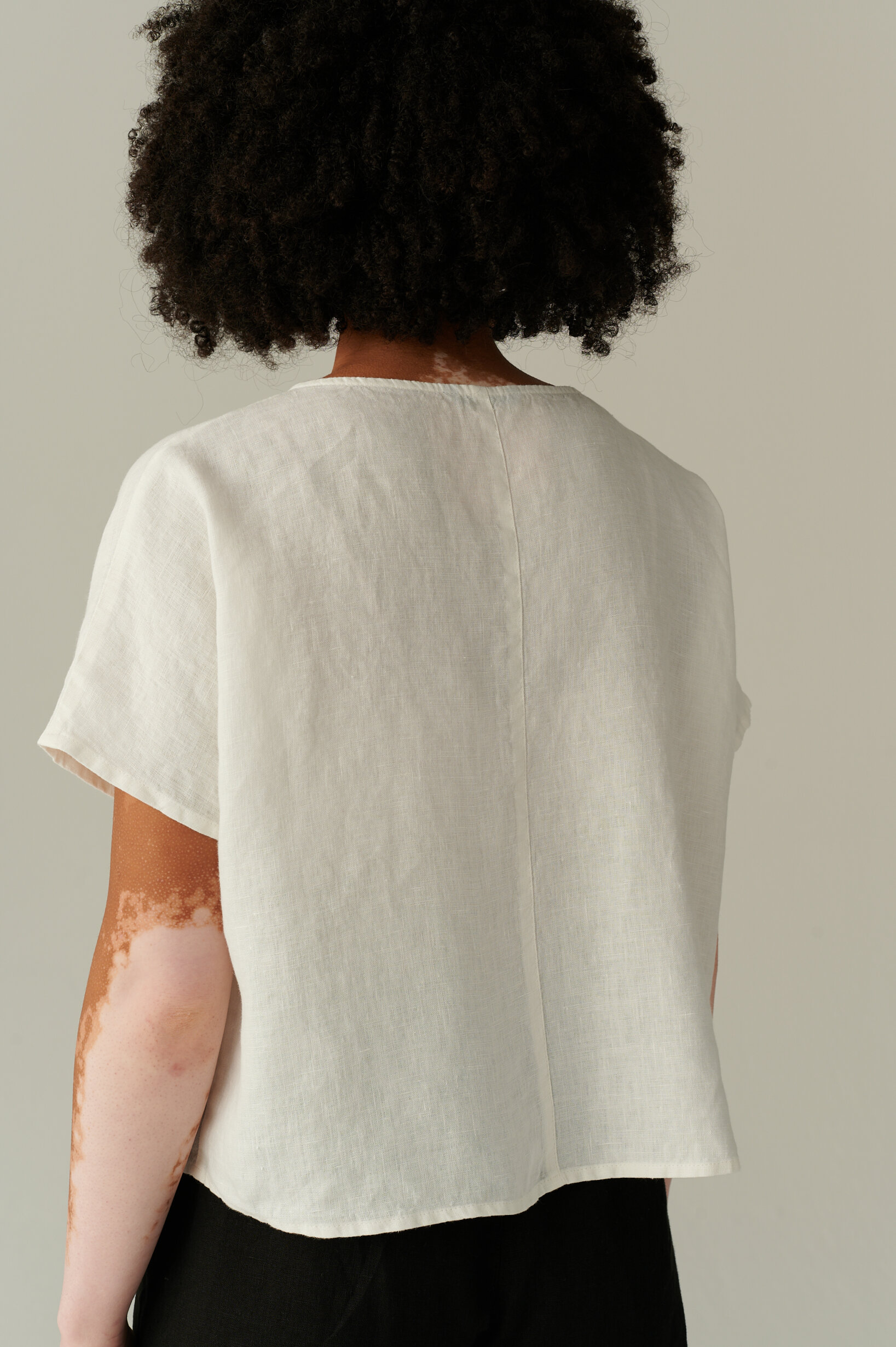 The back view of a loose fitting linen top with a decorative back seam