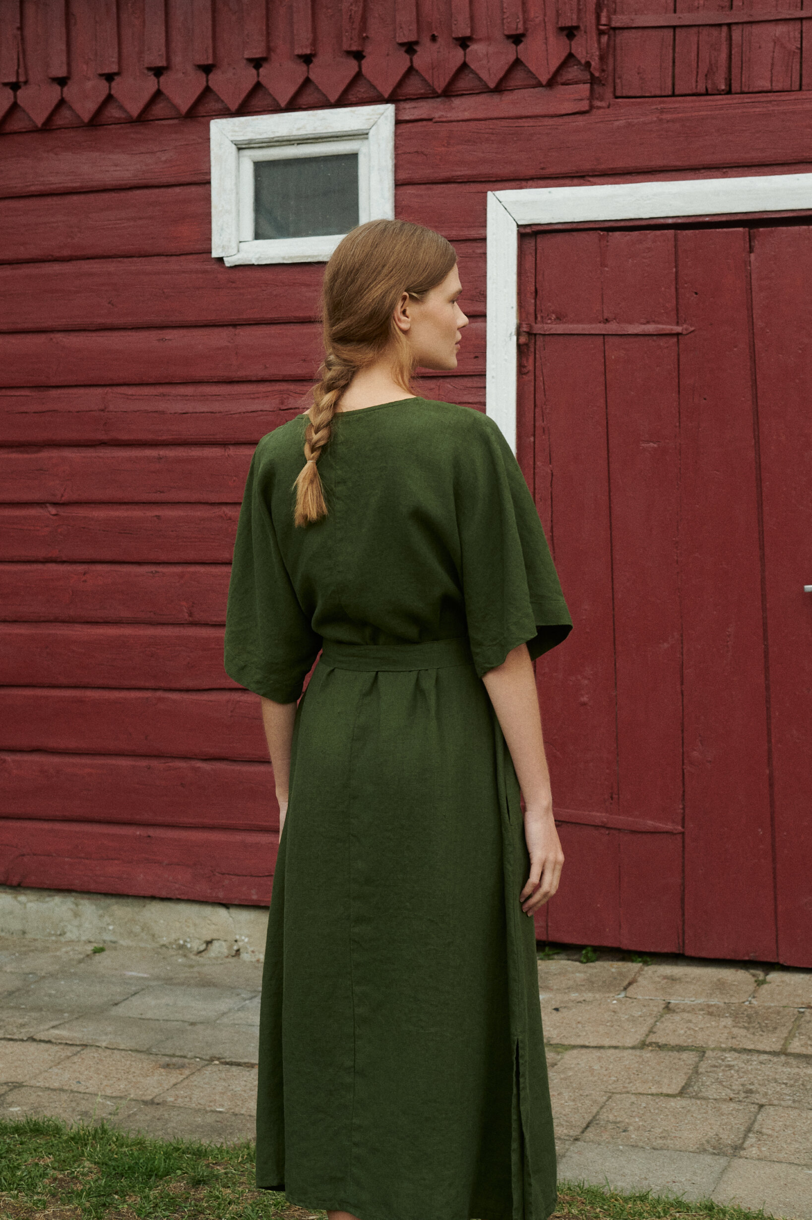 a back view of oversized linen dress in forest green with a 3/4 length sleeves and belt