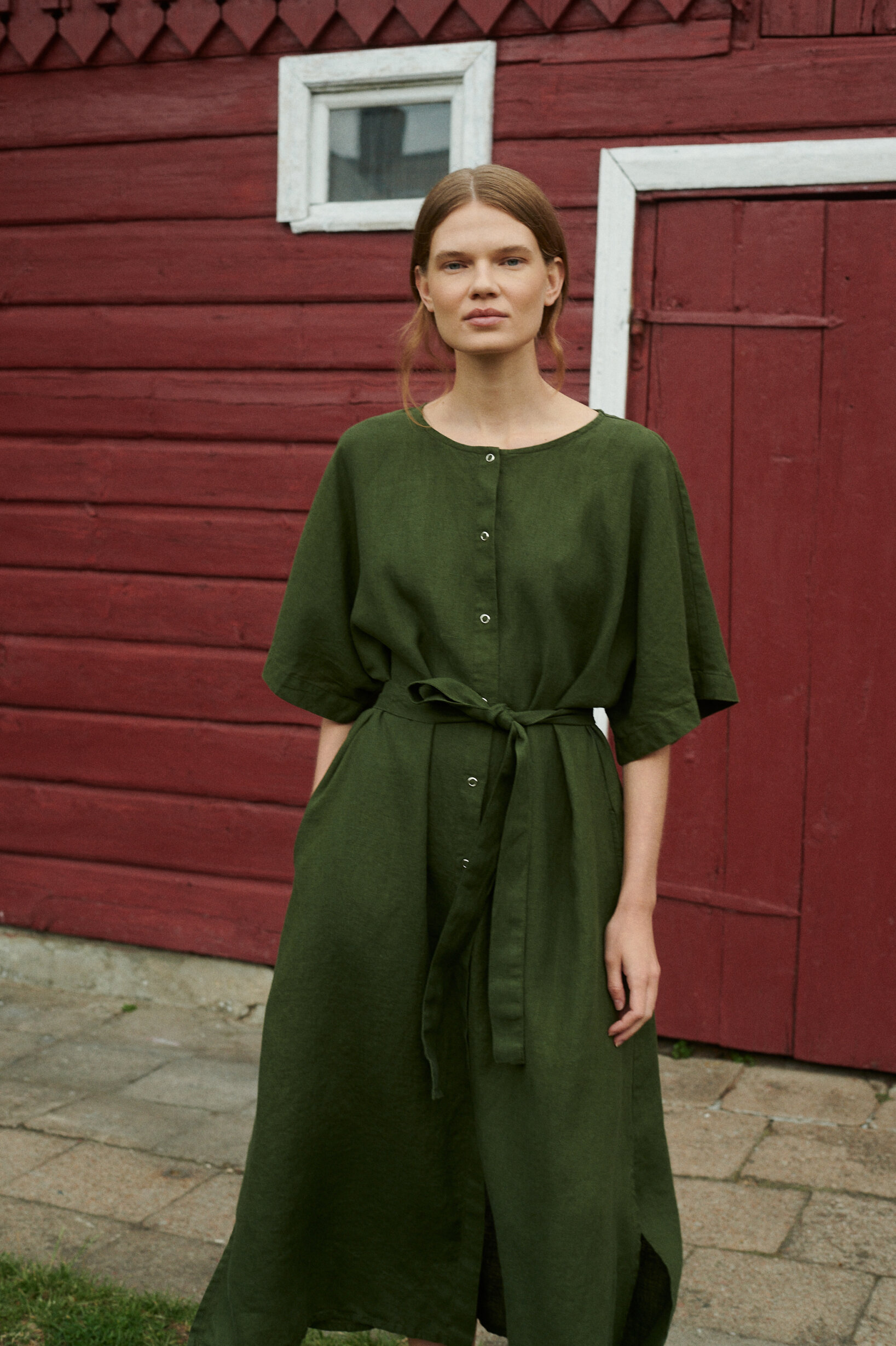 model posing in an oversized summer linen dress in forest green with snap openings