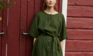 model wearing oversized summer linen dress in forest green with snap openings in a garden