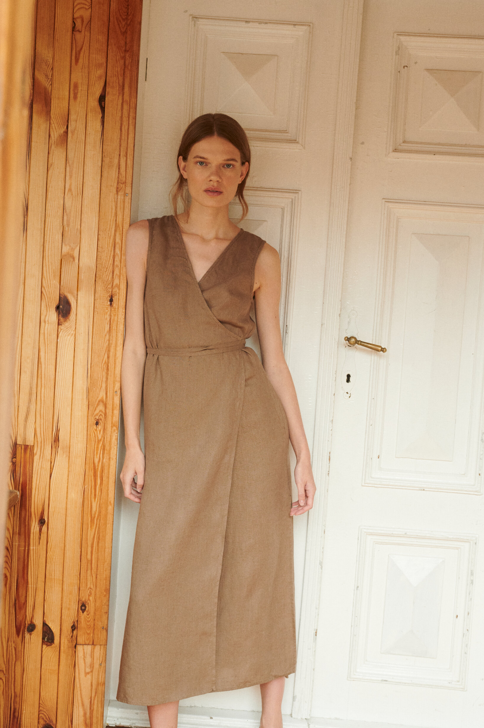 model wearing a V-neck linen wrap dress in midi length in cacao color