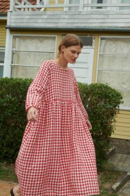 model wearing an oversized linen dress with full length sleeves in red gingham linen