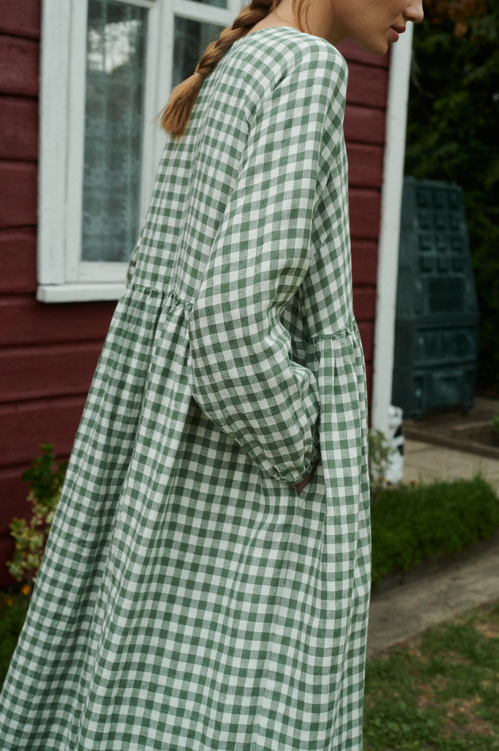a close up shot of model posing with an oversized green gingham linen dress with full length sleeves and pockets