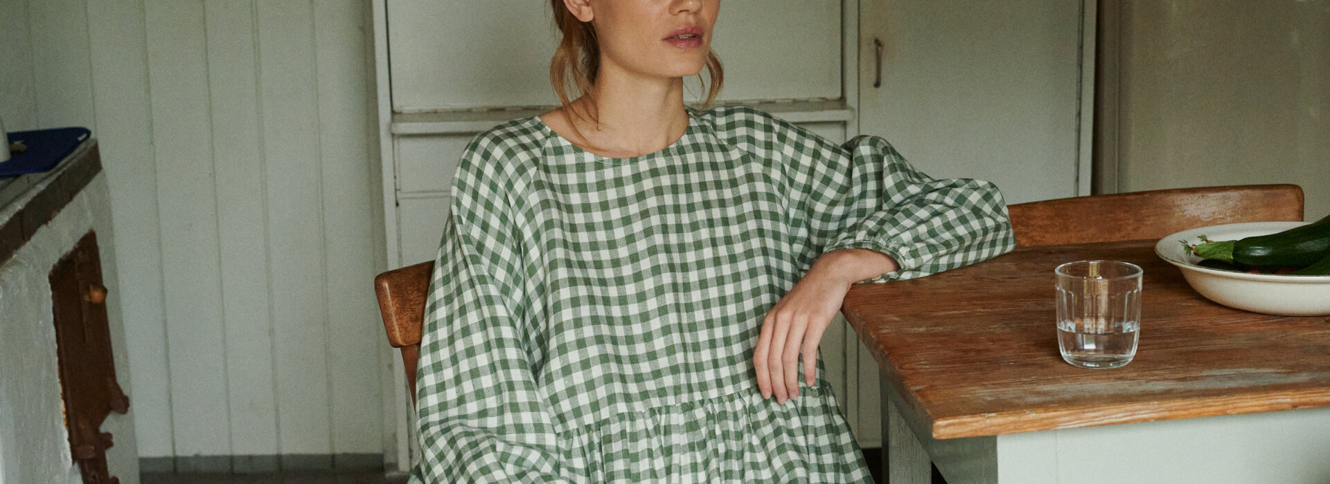 model posing with an oversized green gingham linen dress with full length sleeves