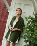 a model posing in short sleeved linen shirt in forest green matched with wrap top and wide shorts in milky white linen