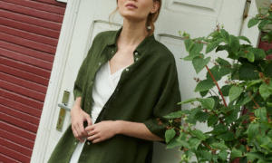 a model posing in short sleeved linen shirt in forest green matched with wrap top and wide shorts in milky white linen