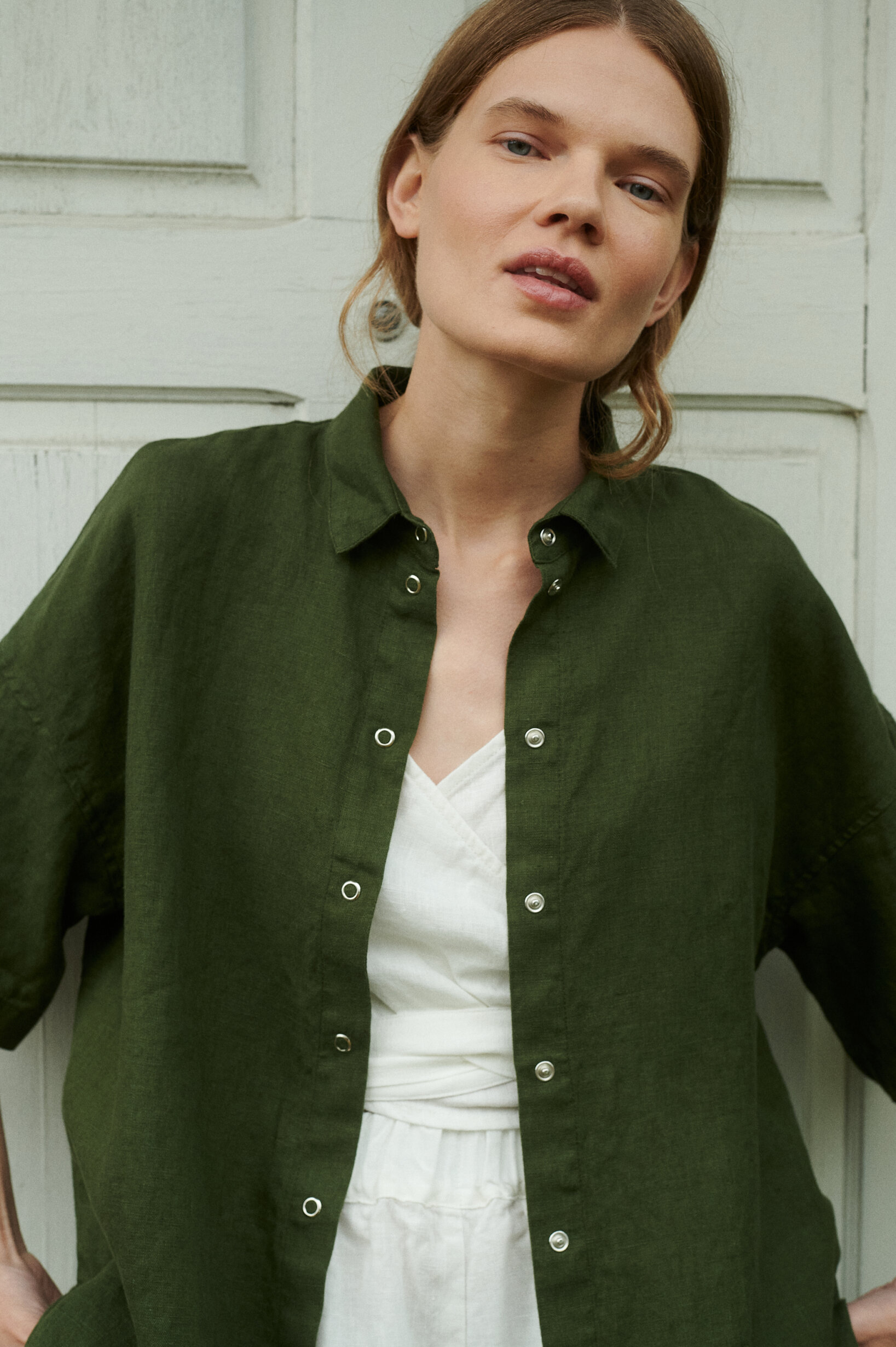 a woman wearing summer linen shirt with snap closure in forest green and milky white linen wrap top