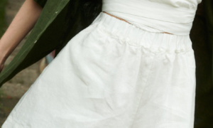 woman wearing natural linen wide summer shorts in milky white and v-neck wrap top along with forest green shirt