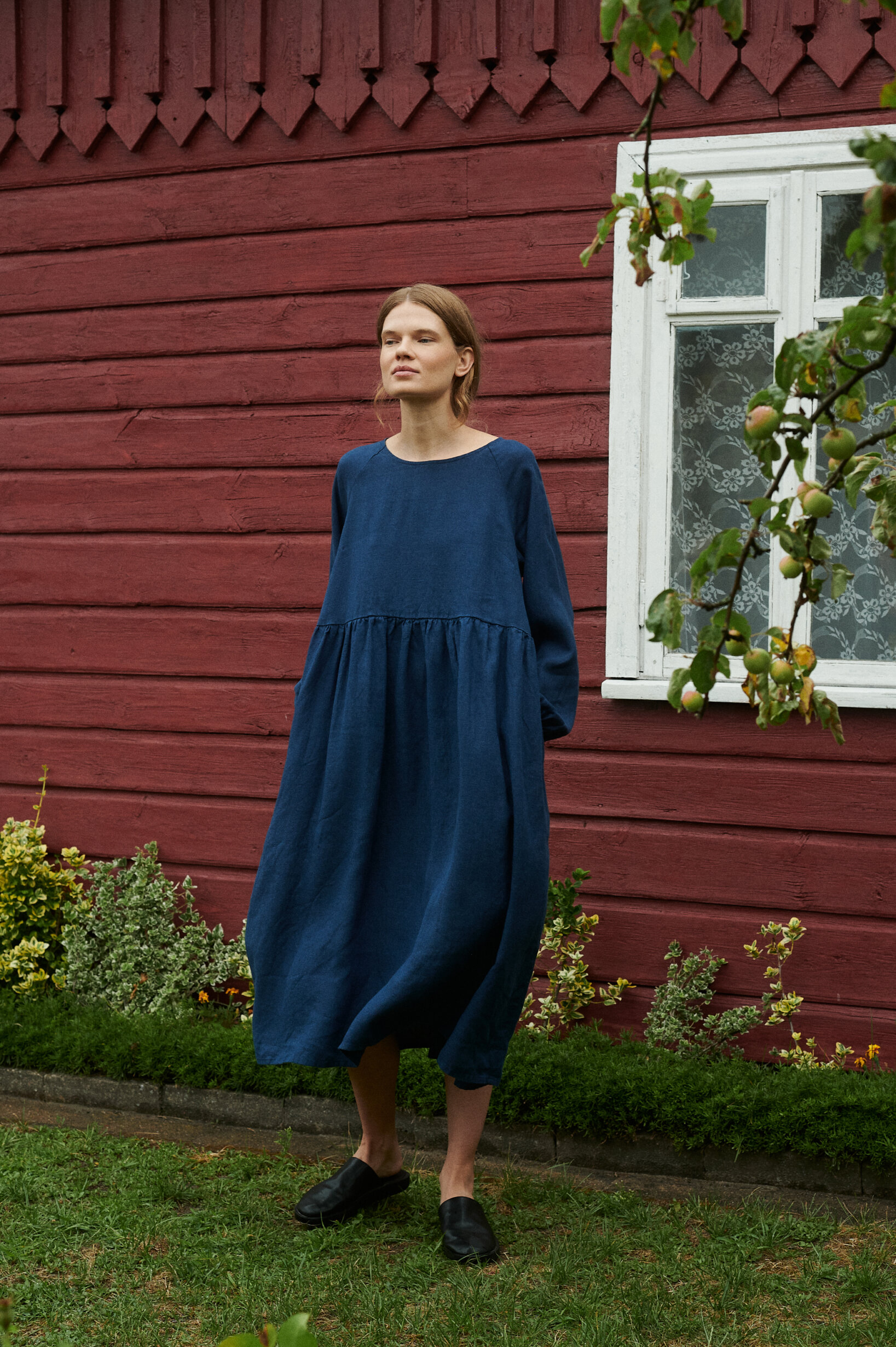 a model near the summer cottage wearing oversized linen dress in navy blue natural linen with pockets