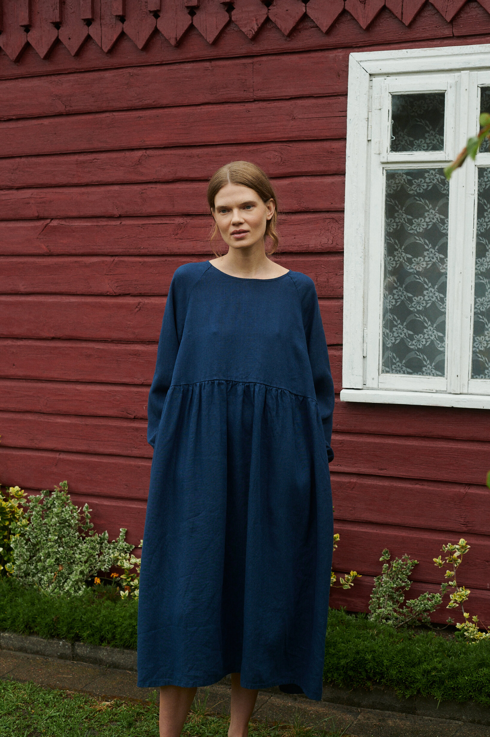 model wearing oversized linen dress in navy blue natural linen near the summer cottage