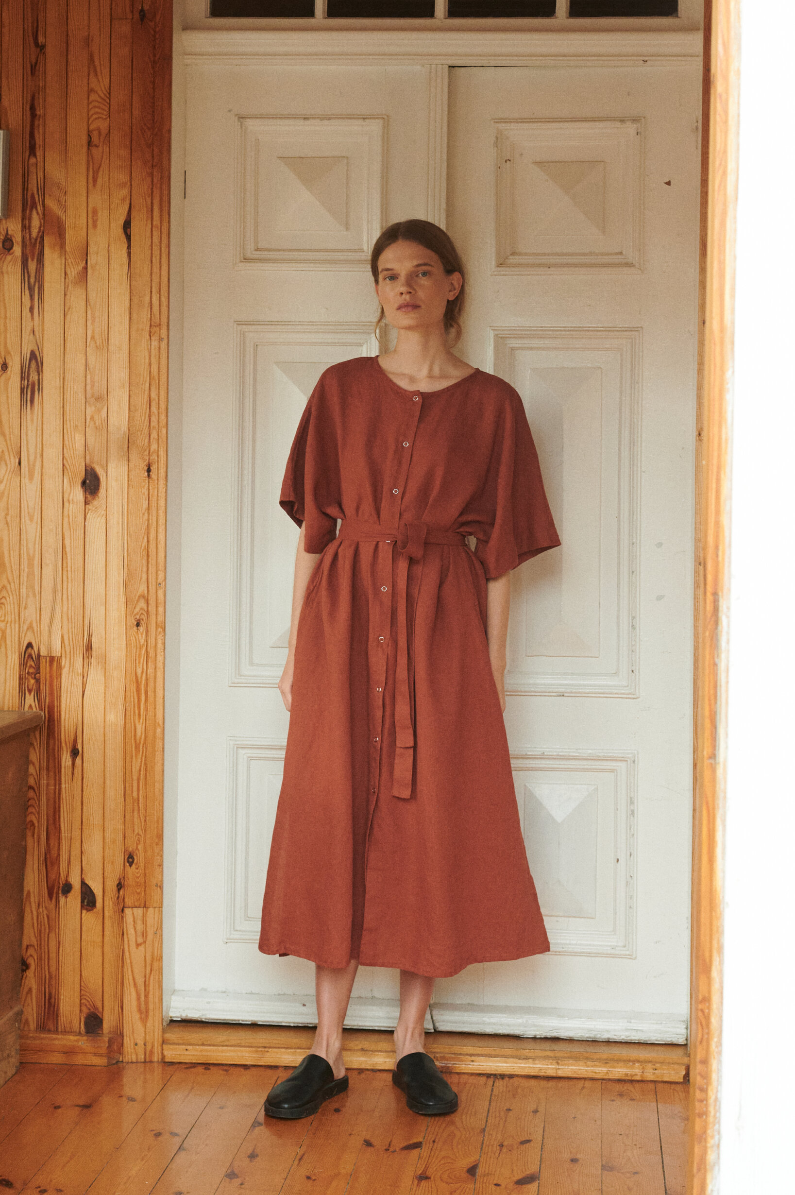 a woman wearing oversized linen dress in terracotta with snap openings and belt