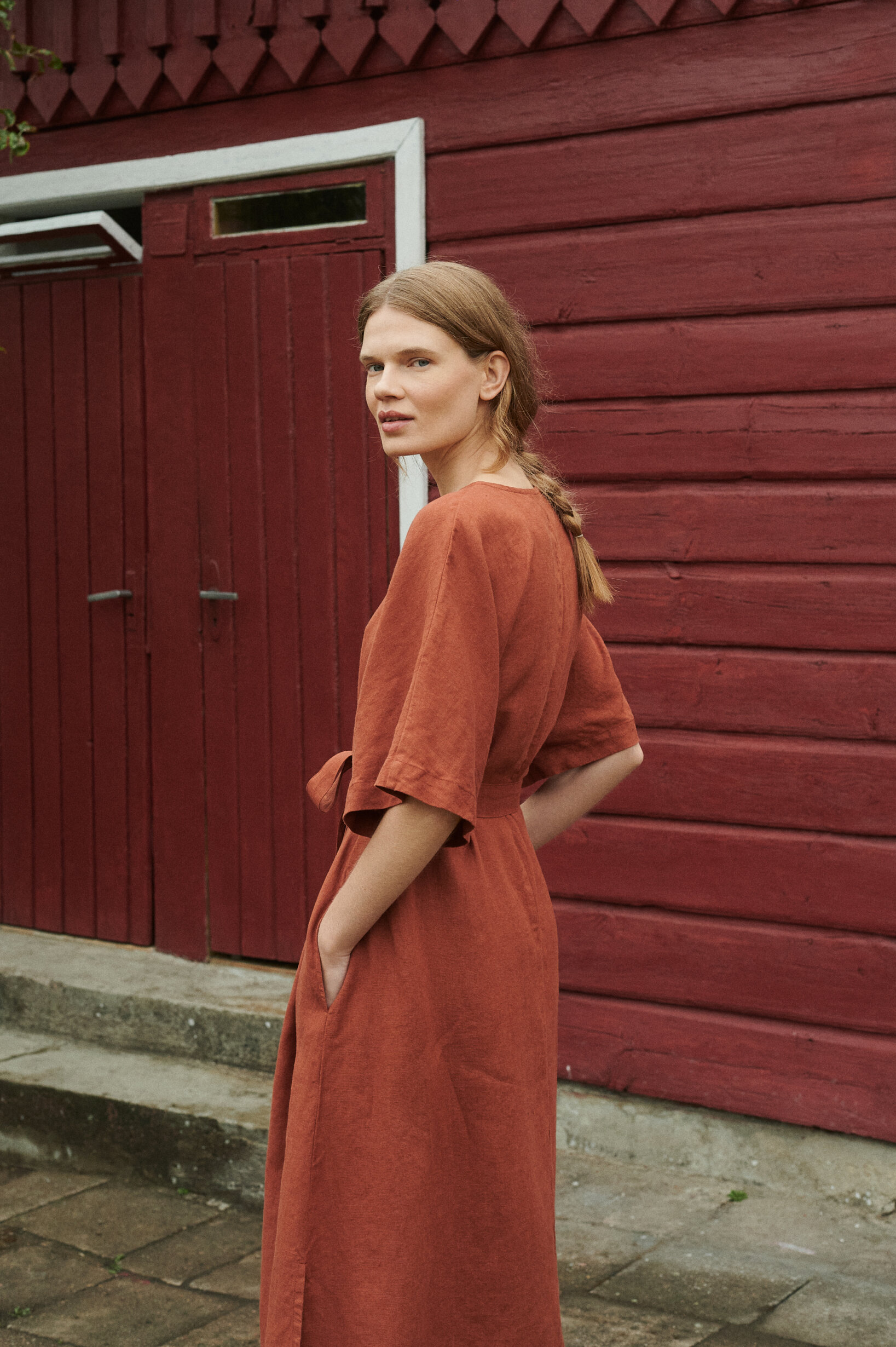 model posing in oversized linen dress in terracotta with snap openings and pockets