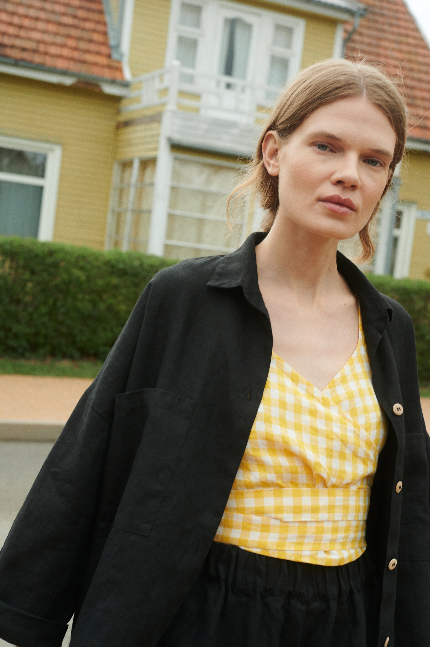 a close up shot of model wearing black linen shirt and yellow gingham wrap top
