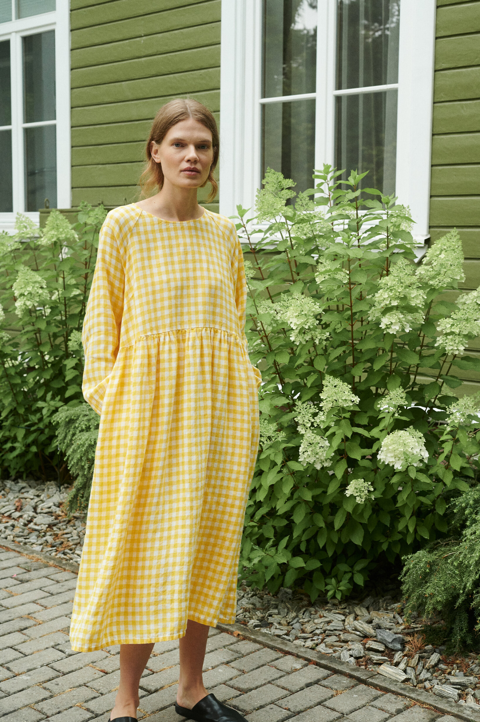 model in a garden wearing a yellow gingham linen dress in oversized fit and full length sleeves