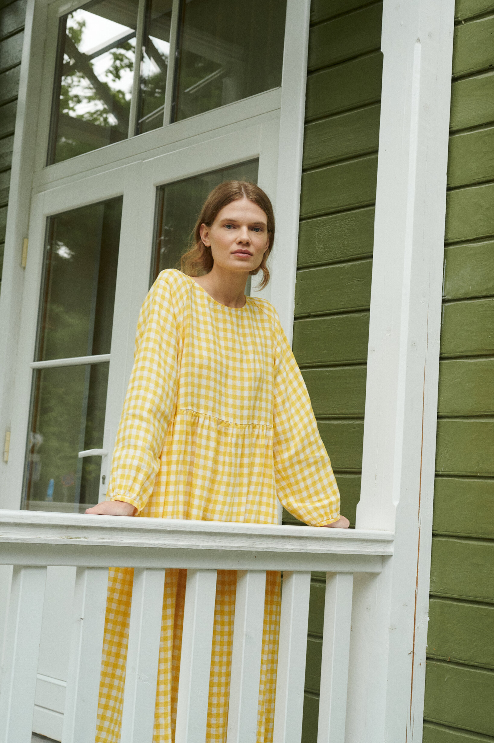 model posing wearing a yellow gingham linen dress in oversized fit and full length sleeves for summer