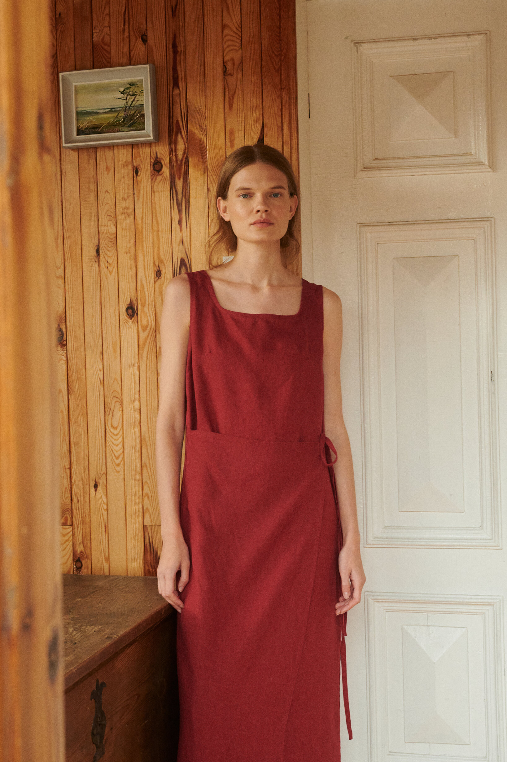 model posing with a sleeveless summer wrap dress in burgundy red linen