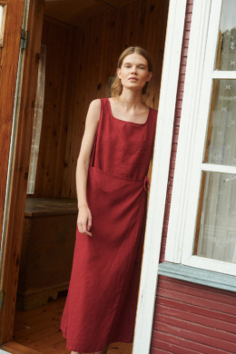model wearing a bright sleeveless summer wrap dress in burgundy red linen