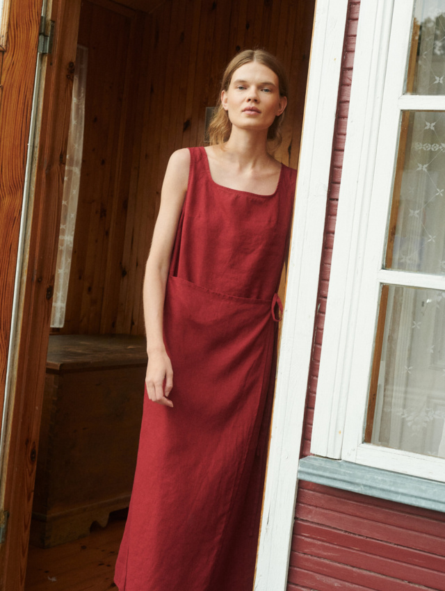 model wearing a bright sleeveless summer wrap dress in burgundy red linen