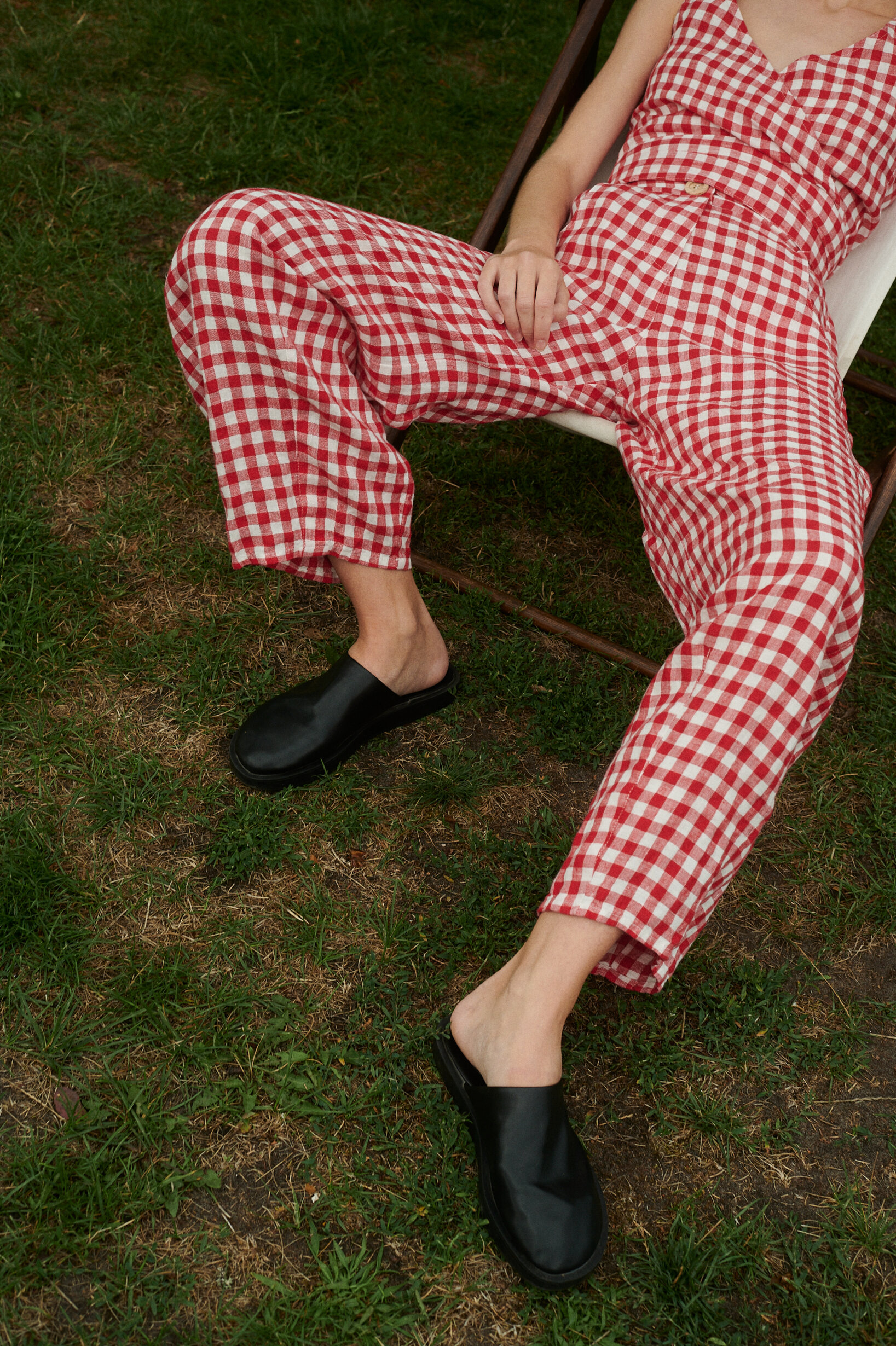 a close up shot of woman wearing red gingham linen set of trousers and wrap top