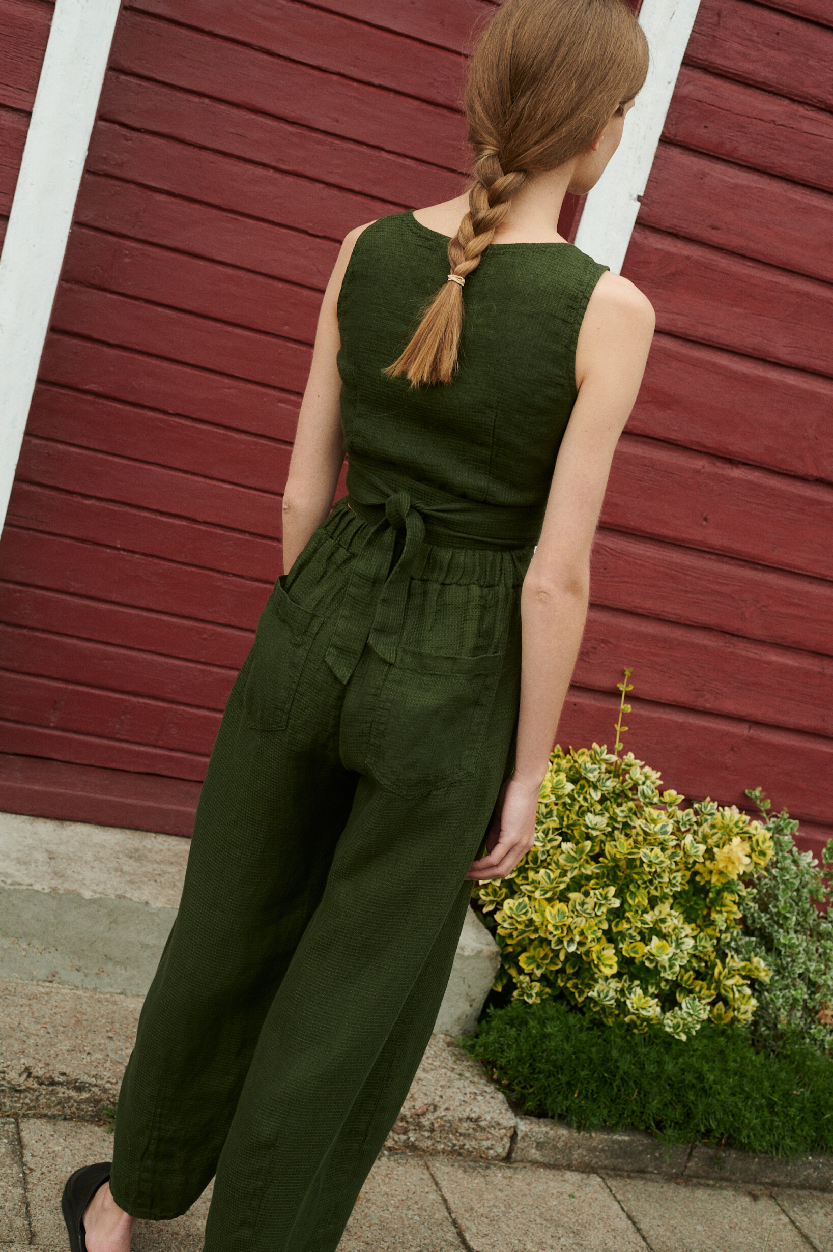 a back shot of model wearing summer set of waffle linen trousers and wrap top in forest green
