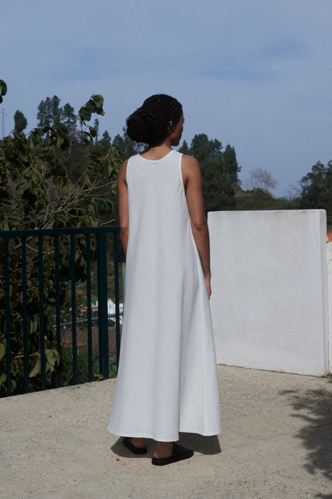 Back view of Alba linen dress in milky white: sleeveless, flowing maxi length, bias-cut creating graceful pleats.
