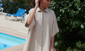 Woman posing in an extra oversized maxi beige linen dress with loose-fitting sleeves and a shirt collar