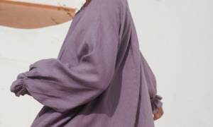 Model in a flowy oversized mini linen dress with long sleeves and elasticated cuffs