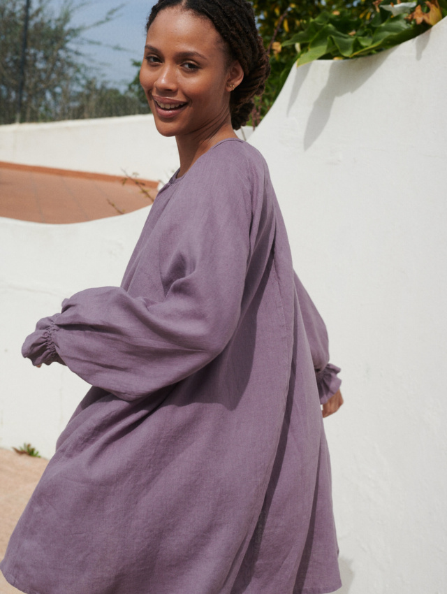 Model in a flowy oversized mini linen dress with long sleeves and elasticated cuffs