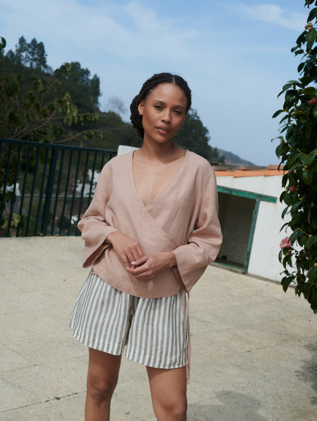 Model wearing lightweight cacao stripes linen shorts and an oversized long sleeve peach linen wrap top outfit