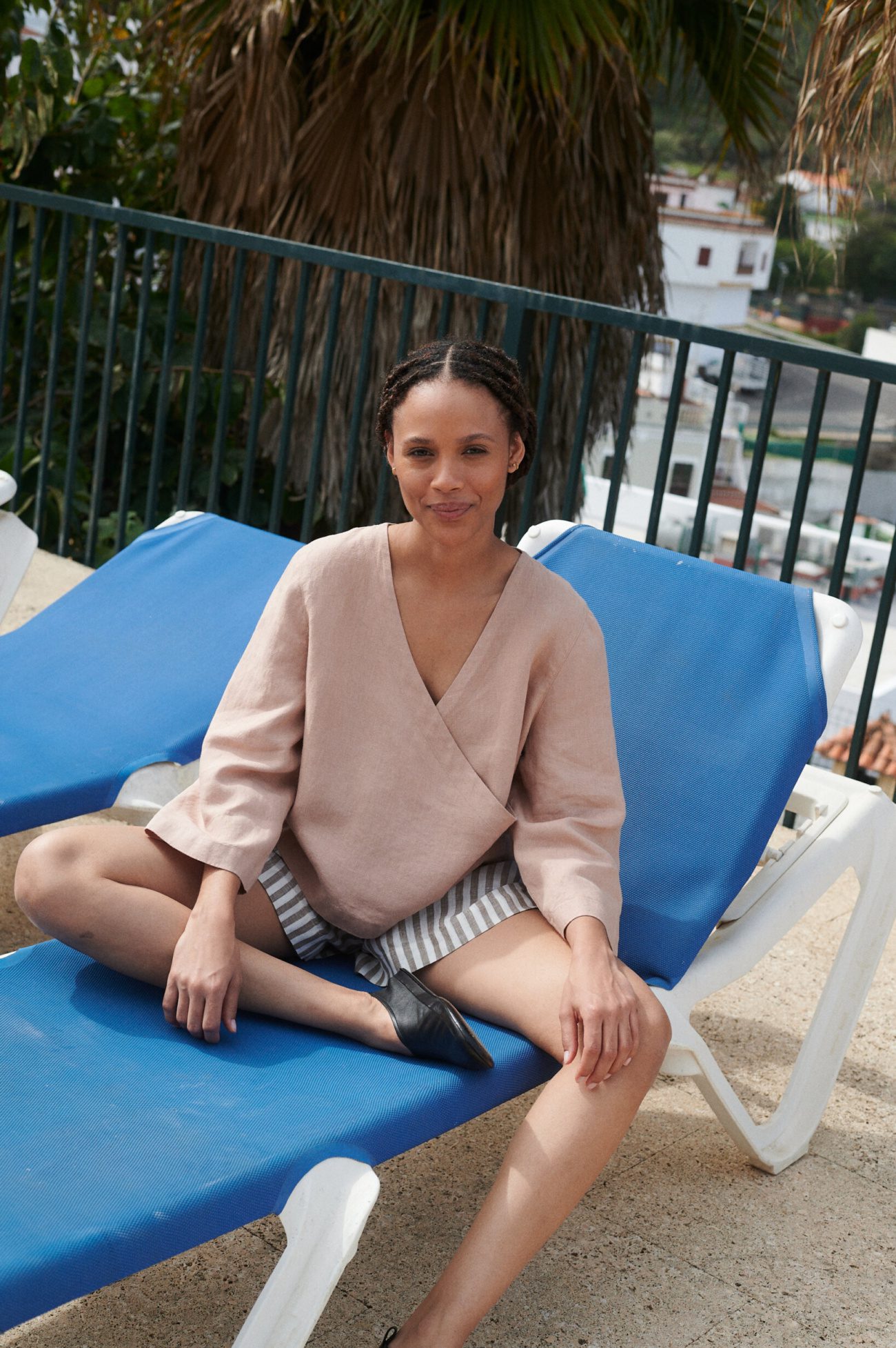 Model wearing an oversized linen peach wrap top and striped linen shorts