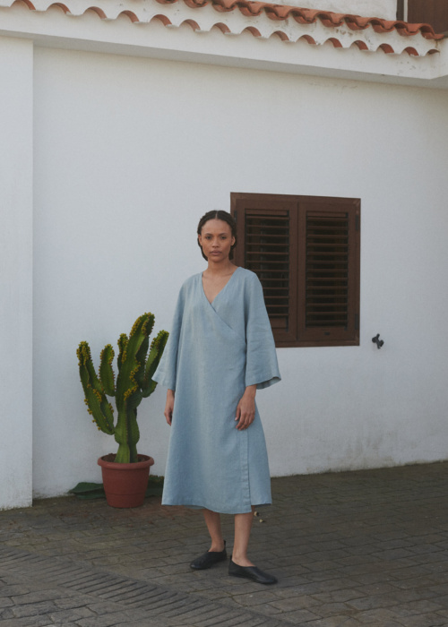 Woman in an oversized sea green midi linen wrap dress with long loose sleeves