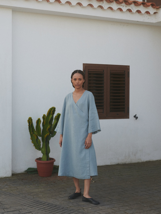 Woman in an oversized sea green midi linen wrap dress with long loose sleeves