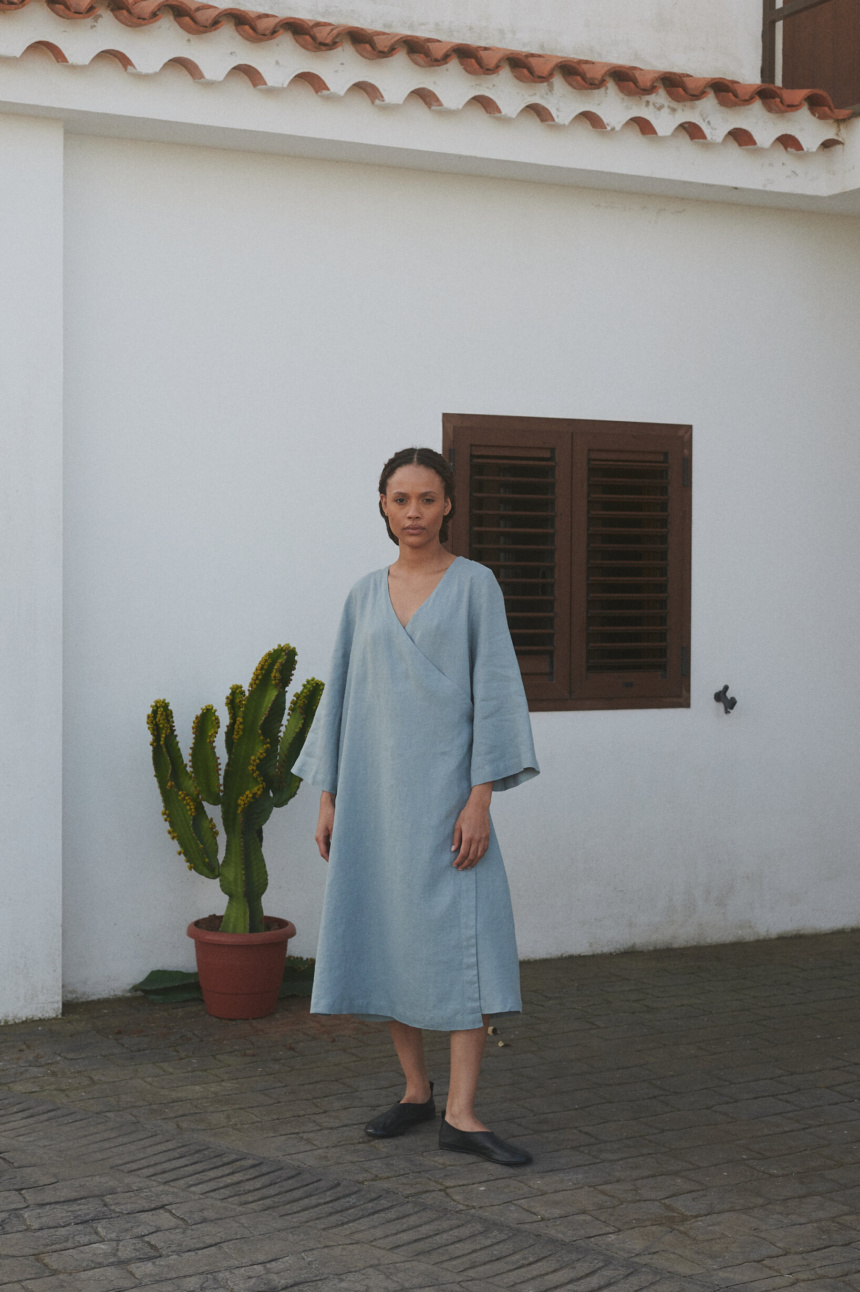 Woman in an oversized sea green midi linen wrap dress with long loose sleeves